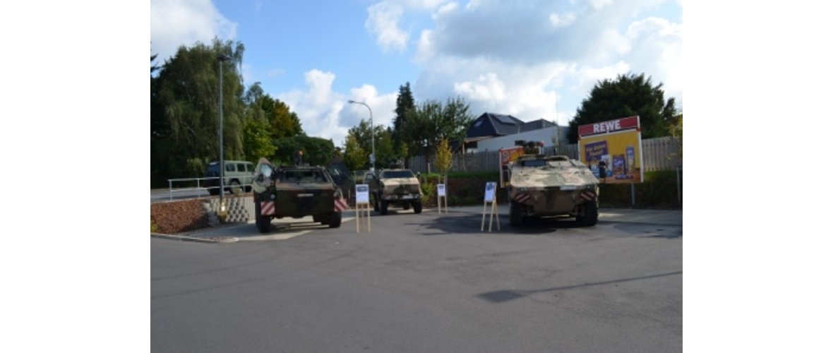 Drei Bundeswehr Fahrzeuge stehe auf einem Parkplatz und sind Ausgestellt.