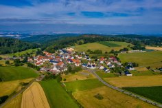 Luftaufnahme Hauptschwenda Luftaufnahme des Stadtteils Hauptschwenda im Sommer. Umgeben von Feldern und Äckern, leicht bedeckter Himmel.