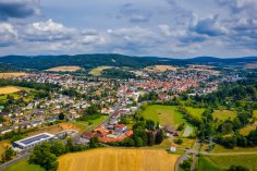 Luftaufnahme Neukirchen Luftaufnahme des Stadtteils Neukirchen im Sommer. Im Vordergrund ein gelbes Stoppelfeld, im Hintergrund eine hügelige Waldlandschaft.
