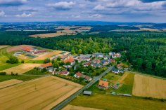 Luftaufnahme Wincherode Luftaufnahme des Stadtteils Wincherode im Sommer. Im Vordergrund links sieht man ein Feld, rechts eine Wiese. Links mittig im Bild ist ein großer Stall zu sehen. Hinter Wincherode ist ein weitläufiger Wald zu sehen, im weiten Hintergrund dann wieder einige Felder unter leicht bedecktem Himmel.