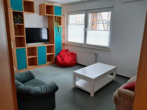 Bild Jugendtreff der Stadt Neukirchen mit einem Regal in dem ein Fernseher steht sowie links einen Sessel und rechts einem Sofa mit Couchtisch