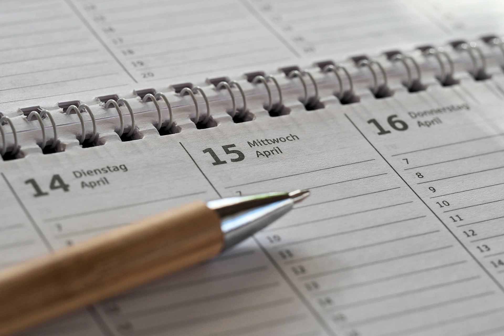 Auf dem Foto ist ein Kalender mit Spiralbindung zu sehen auf dem ein Kuli liegt