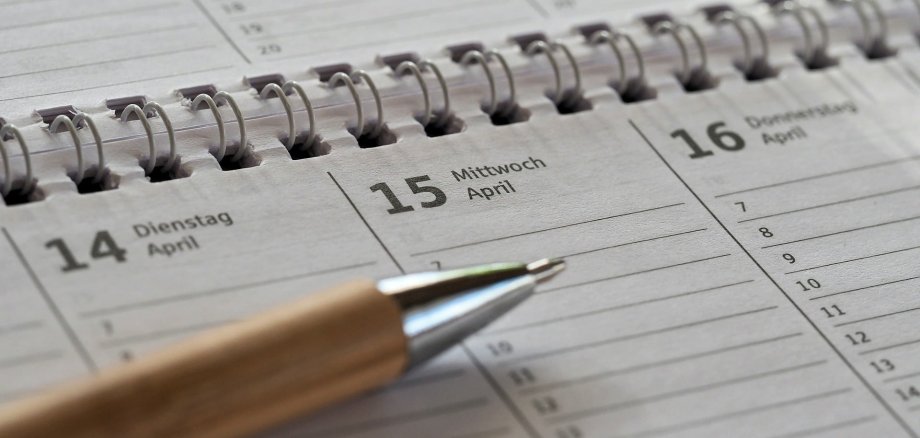 Auf dem Foto ist ein Kalender mit Spiralbindung zu sehen auf dem ein Kuli liegt