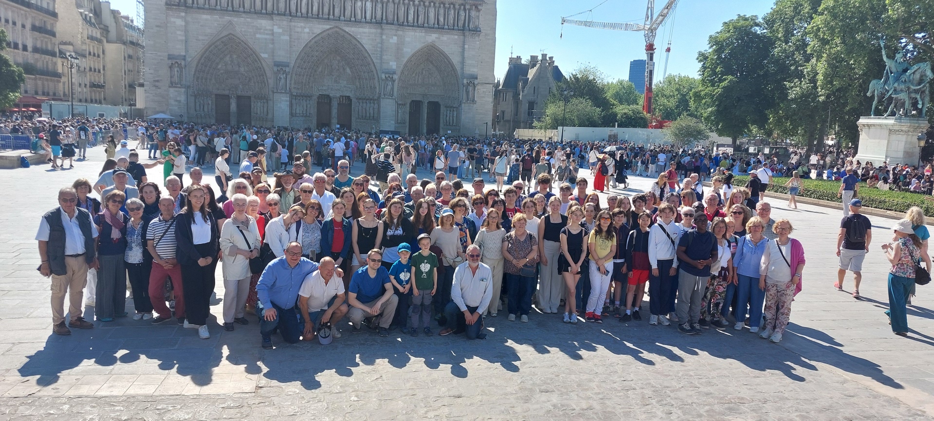 Auf dem Foto ist eine große Gruppe von Menschen vor der Kathedrale von Notre Dame in Paris zu sehen