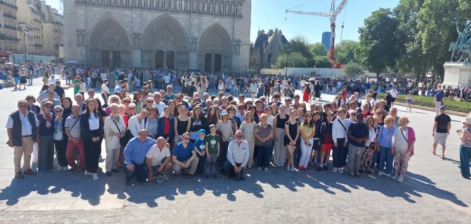 Auf dem Foto ist eine große Gruppe von Menschen vor der Kathedrale von Notre Dame in Paris zu sehen