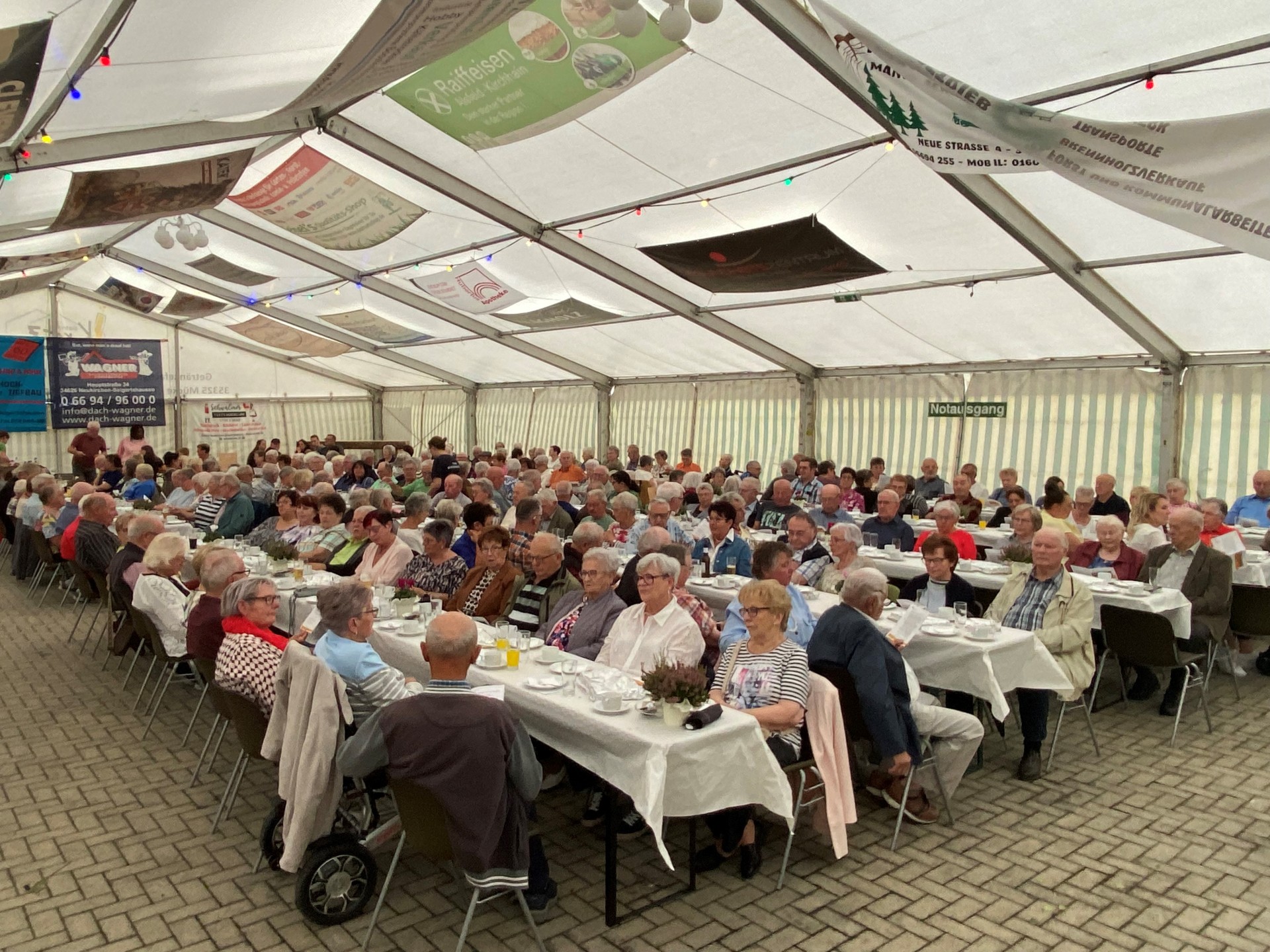 Auf dem Foto sind Seniorinnen und Senioren zu sehen, die an Bierzeltgarnituren in einem Festzelt sitzen.