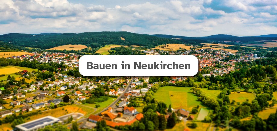 Luftaufnahme der Stadt Neukirchen im Hintergrund mit weißem Feld mittig in dem der Text "Bauen in Neukirchen" zu lesen ist.