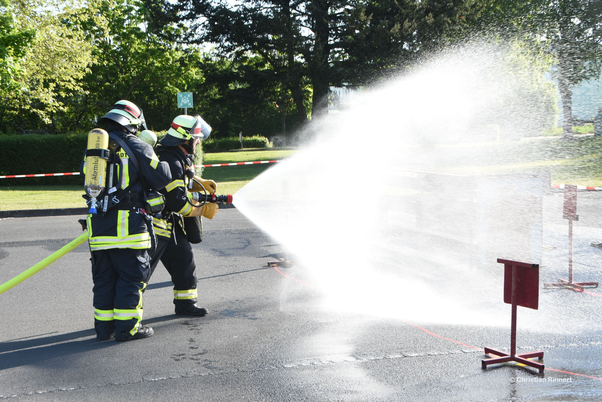 Auf dem Foto sind zwei Feuerwehrleute zu sehen, die einen Wasserschlauch halten aus dem Wasser spritzt.