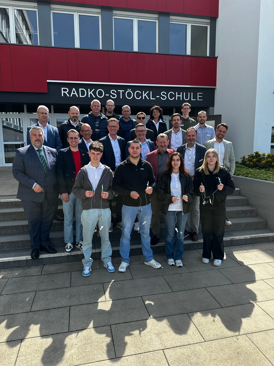 Auf dem Foto sieht man eine Gruppe Auszubildender sowie Landtagsabgeordneter vor der Radko-Stöckl-Schule in Melsungen