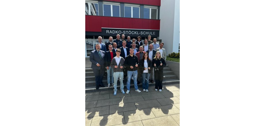 Auf dem Foto sieht man eine Gruppe Auszubildender sowie Landtagsabgeordneter vor der Radko-Stöckl-Schule in Melsungen
