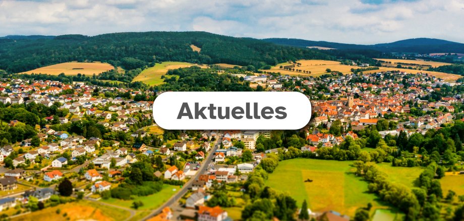 Luftaufnahme der Stadt Neukirchen im Hintergrund mit weißem Feld mittig in dem der Text "Aktuelles" zu lesen ist.