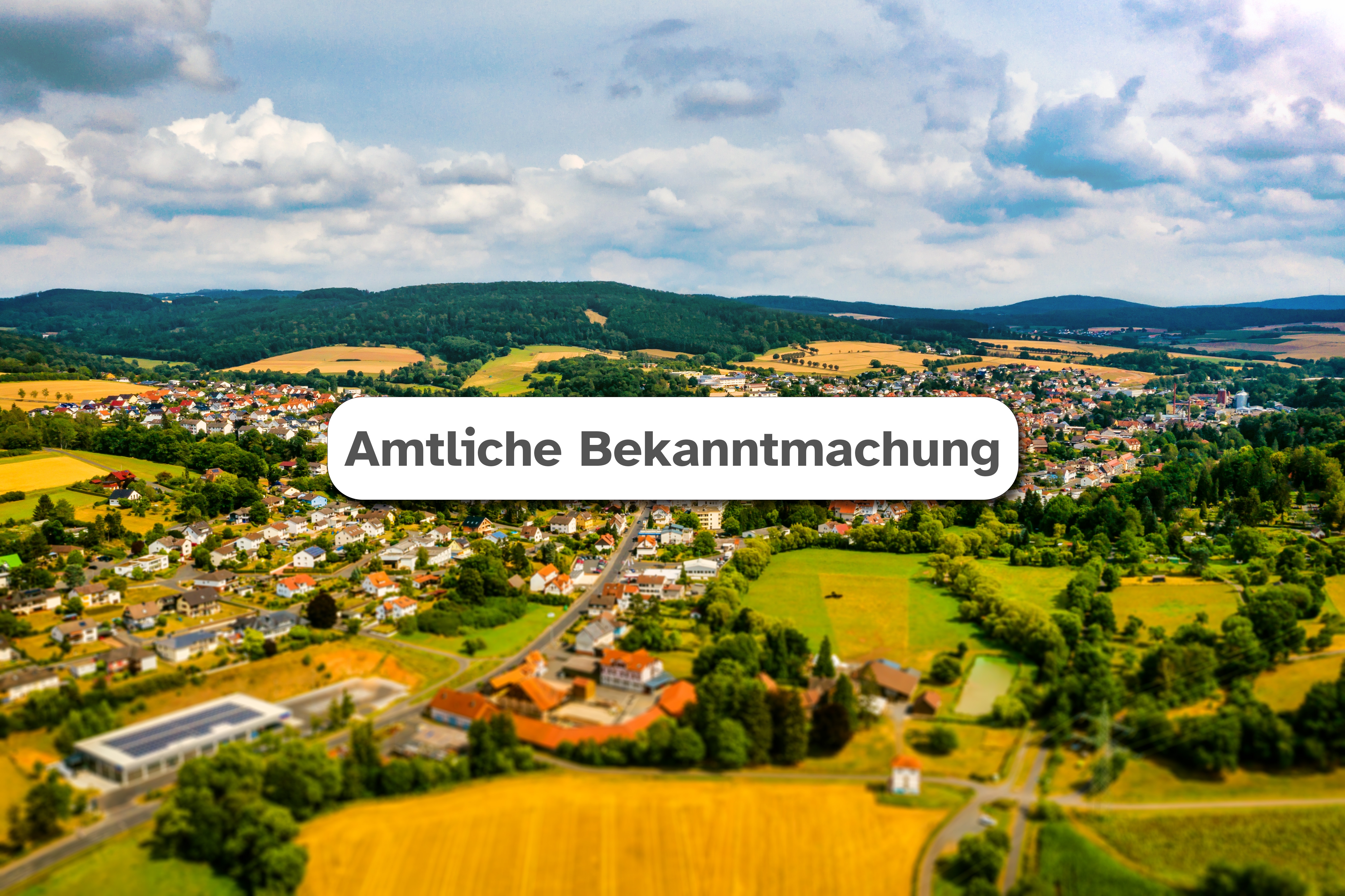 Neukirchen Amtliche Bekanntmachung Luftaufnahme der Stadt Neukirchen im Hintergrund mit weißem Feld mittig in dem der Text "Amtliche Bekanntmachung" zu lesen ist.